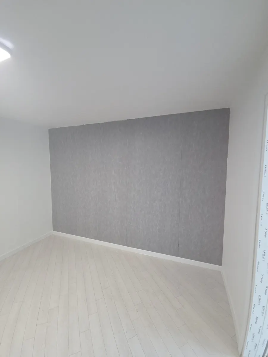 거실 단열결로시공 실제 시공 현장, 한쪽 벽 전체에 회색 단열 마감재가 시공된 방